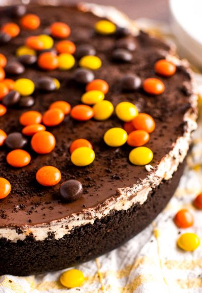 Close up photo of a no bake peanut butter cheesecake topped with Reese's Pieces.