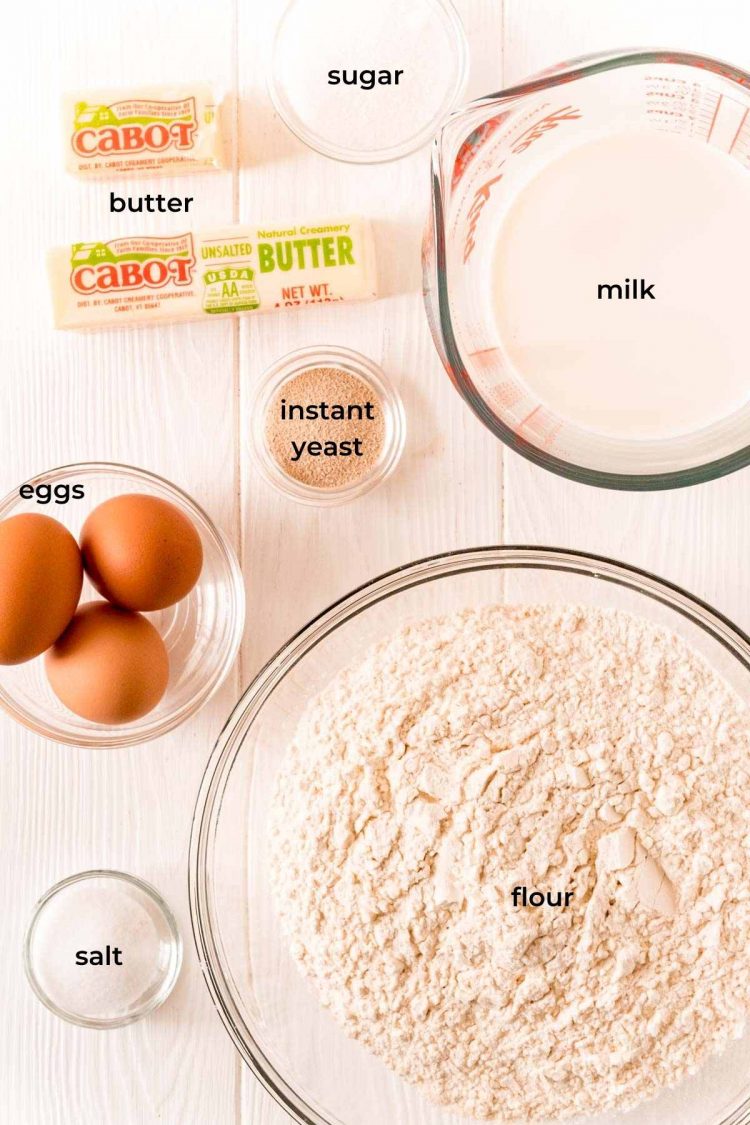 Ingredients to make parker house dinner rolls on a white wood table.