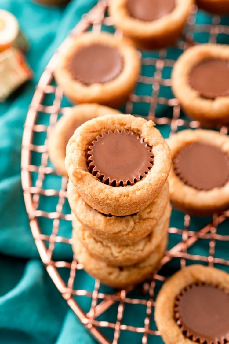 Peanut butter cookies cups on a copper wire rack on a teal napkin.