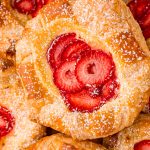 Close up photo of a strawberry danish on a pile of danishes.