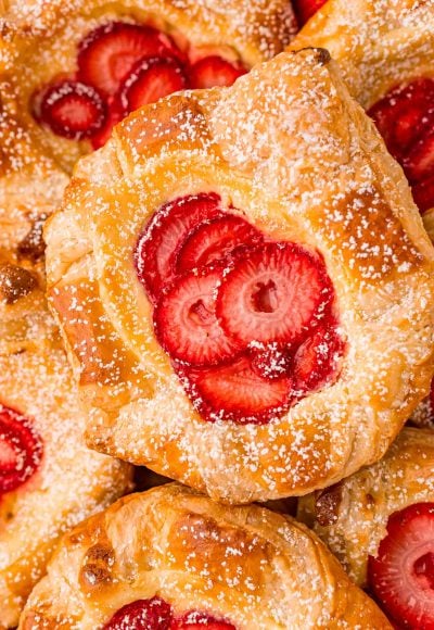 Close up photo of a strawberry danish on a pile of danishes.