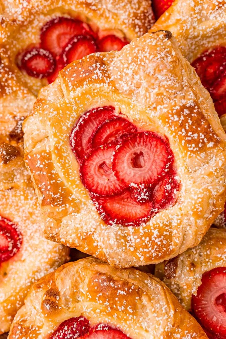 Close up photo of a strawberry danish on a pile of danishes.