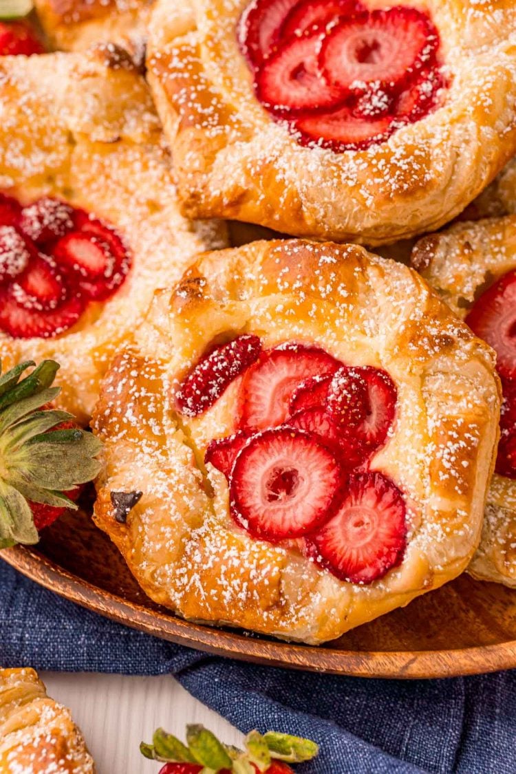 Close up photo of strawberry cream cheese danishes on a wooden plate.