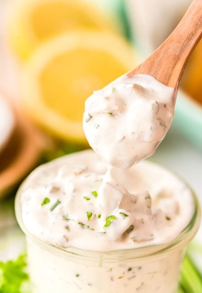 A spoon scooping tartar sauce out of a jar.