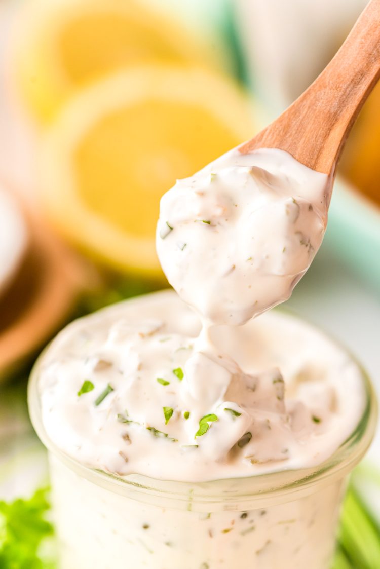 A spoon scooping tartar sauce out of a jar.