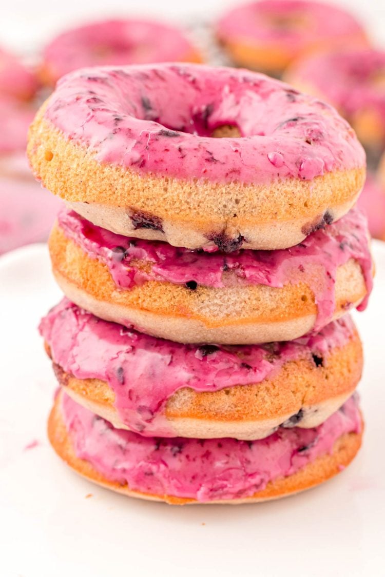 Close up photo of a stack of four blueberry donuts on a marble plate.