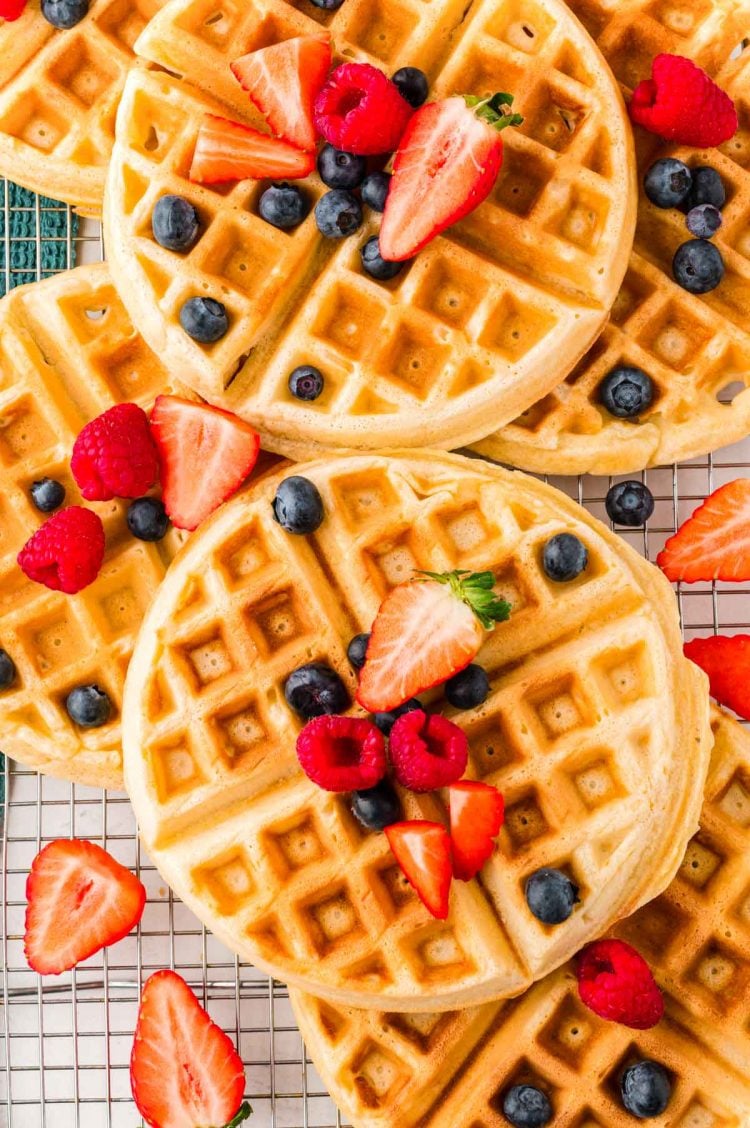 Close up photo of Belgian waffles and fruit on a wire rack.