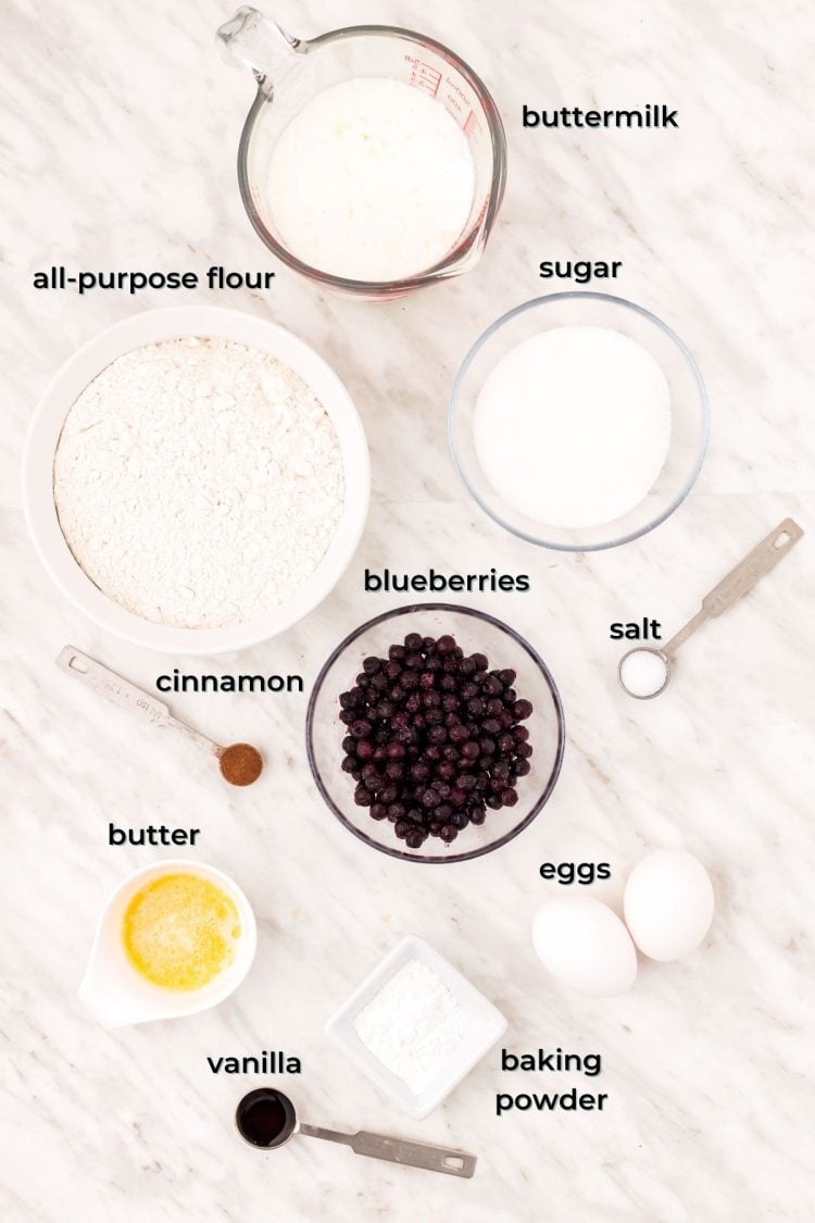 Ingredients to make blueberry donuts on a marble table.