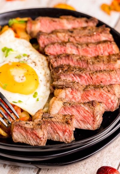 Close up photo of steak and eggs on a black plate.