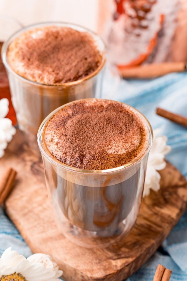 Close up photo of two glass of cafe con miel on a wooden cutting board.