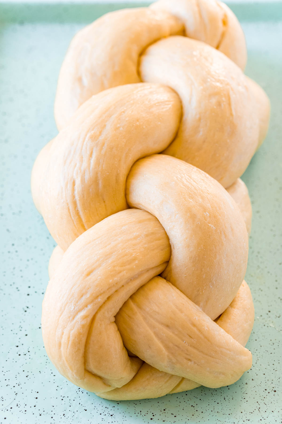 hot to bread challah bread with a loaf on a baking sheet ready to bake.