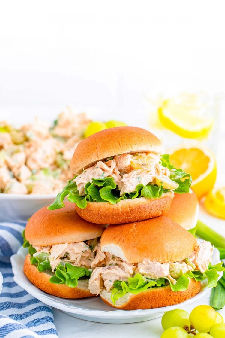 A plate with four chicken salad sandwiches stacked on it.