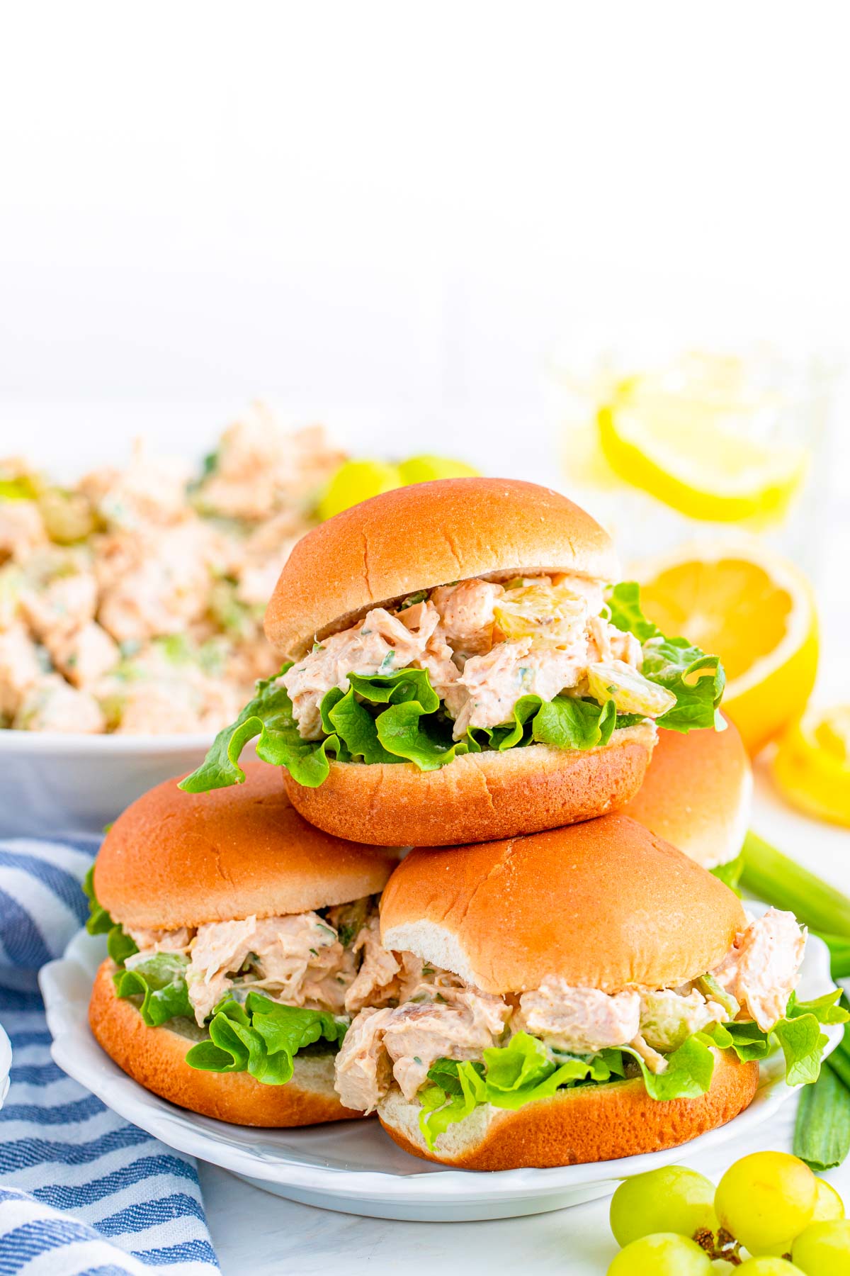 A plate with four chicken salad sandwiches stacked on it.