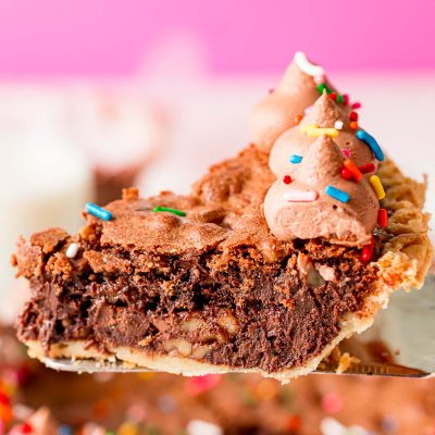 Close up photo of a slice of chocolate toll house pie on a pie server.