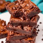 close up photo of a stack of brownies with the top one missing a bite.