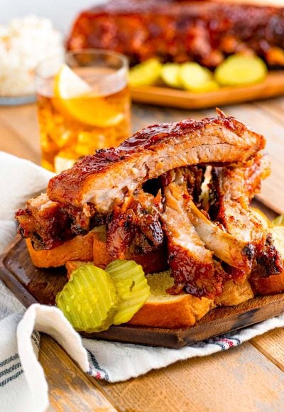 Close up photo of BBQ baby back ribs on a plate with bread and pickles.