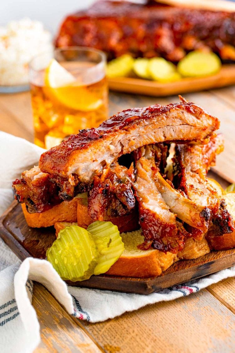 Close up photo of BBQ baby back ribs on a plate with bread and pickles.