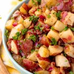 Close up photo of a teal bowl with German potato salad in it.