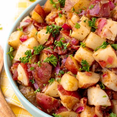 Close up photo of a teal bowl with German potato salad in it.