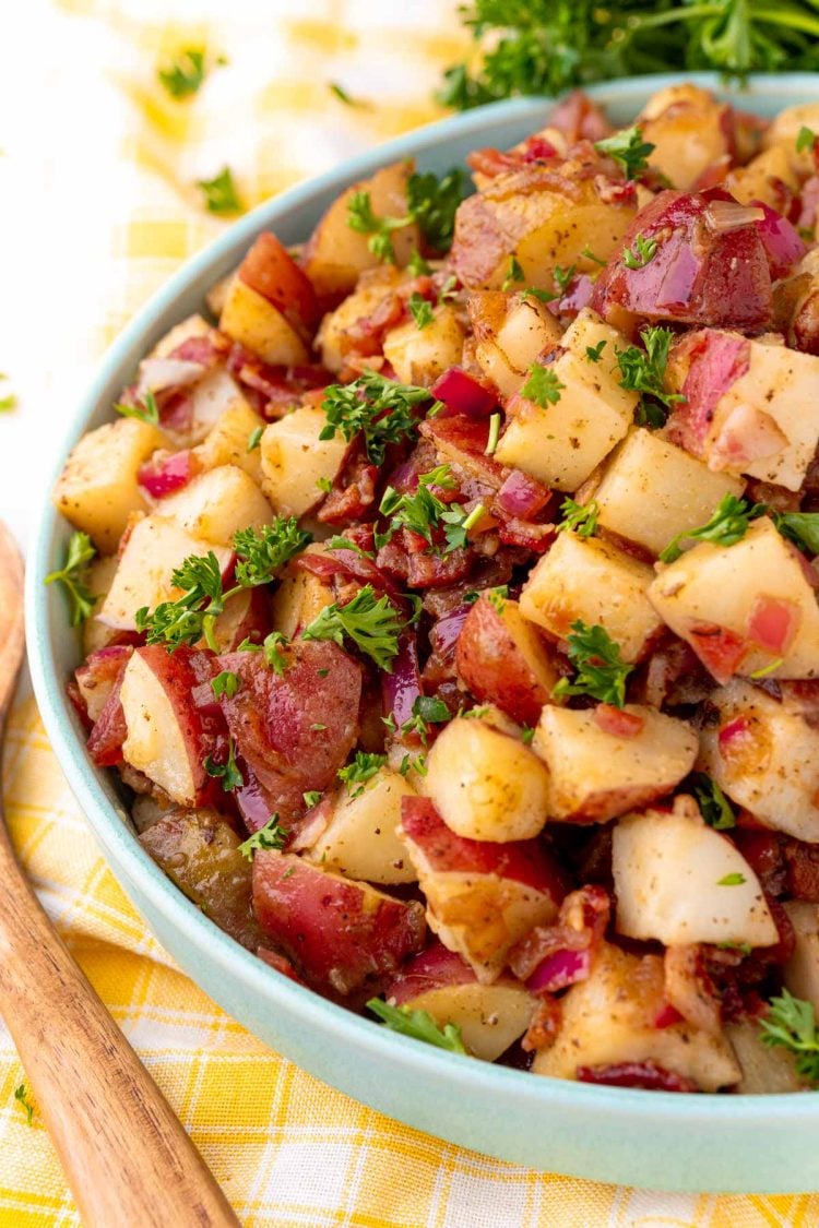 Close up photo of a teal bowl with German potato salad in it.