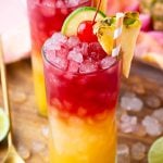 Close up photo of a Malibu Bay Breeze drink garnished with pineapple, cherry, and lime.