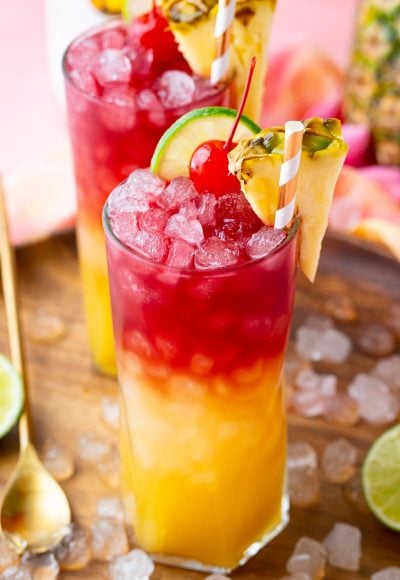 Close up photo of a Malibu Bay Breeze drink garnished with pineapple, cherry, and lime.