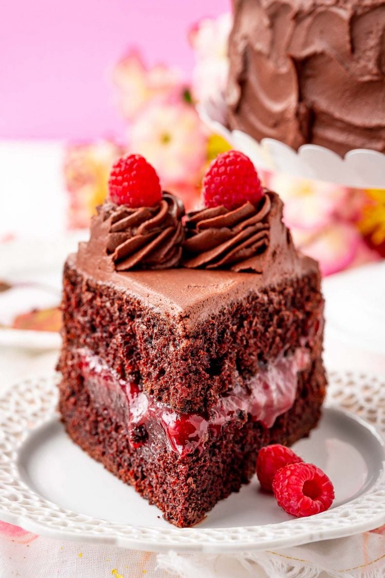 Close up photo of a slice of raspberry chocolate cake on a white plate.