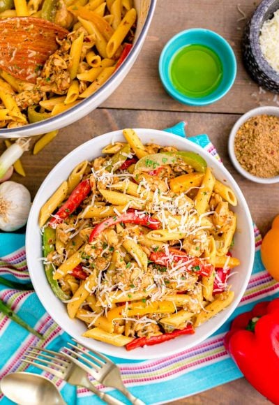 Overhead photo of a bowl of rasta pasta on a wooden table surrounded by ingredients.