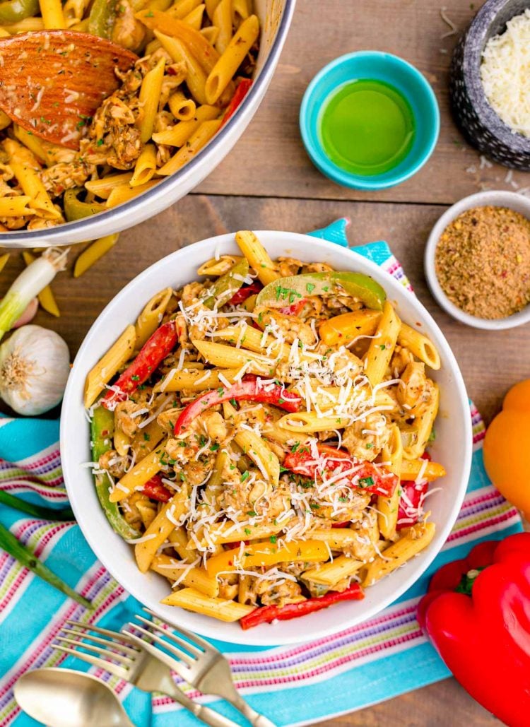 Overhead photo of a bowl of rasta pasta on a wooden table surrounded by ingredients.