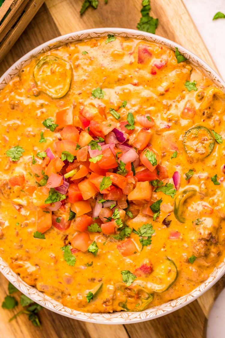 Close up photo of a bowl of smoked queso dip on a wooden cutting board.