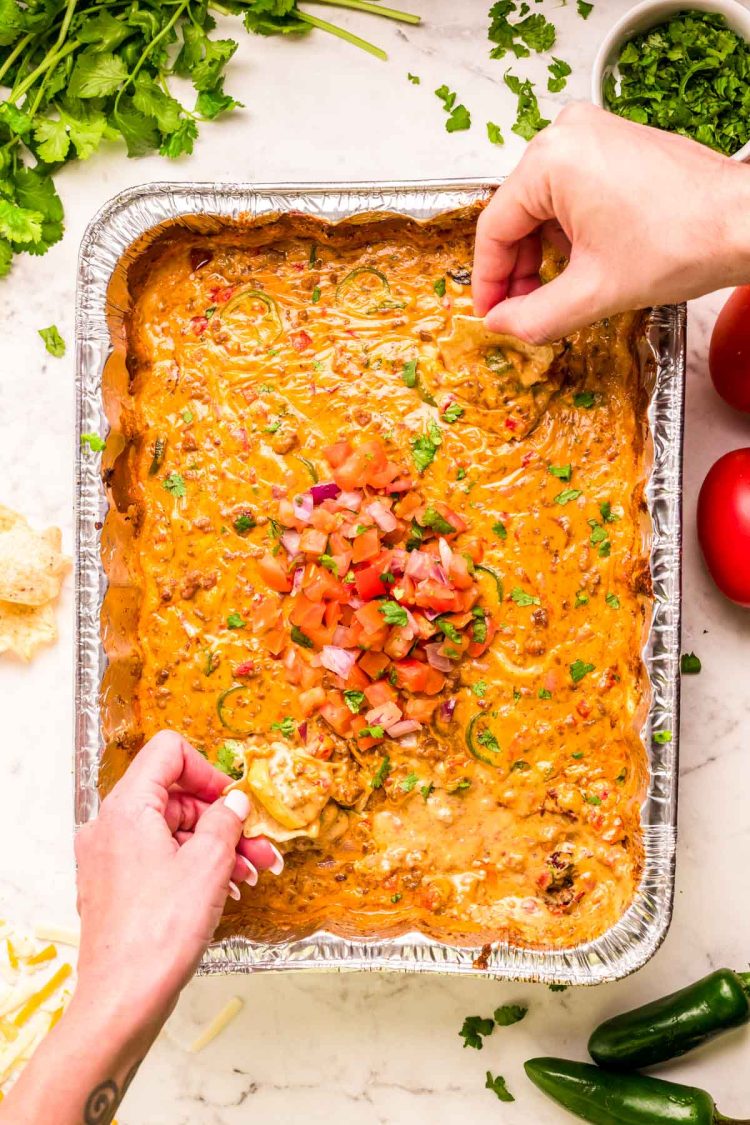 Hands dipping tortilla chips into tiktok smoked queso.