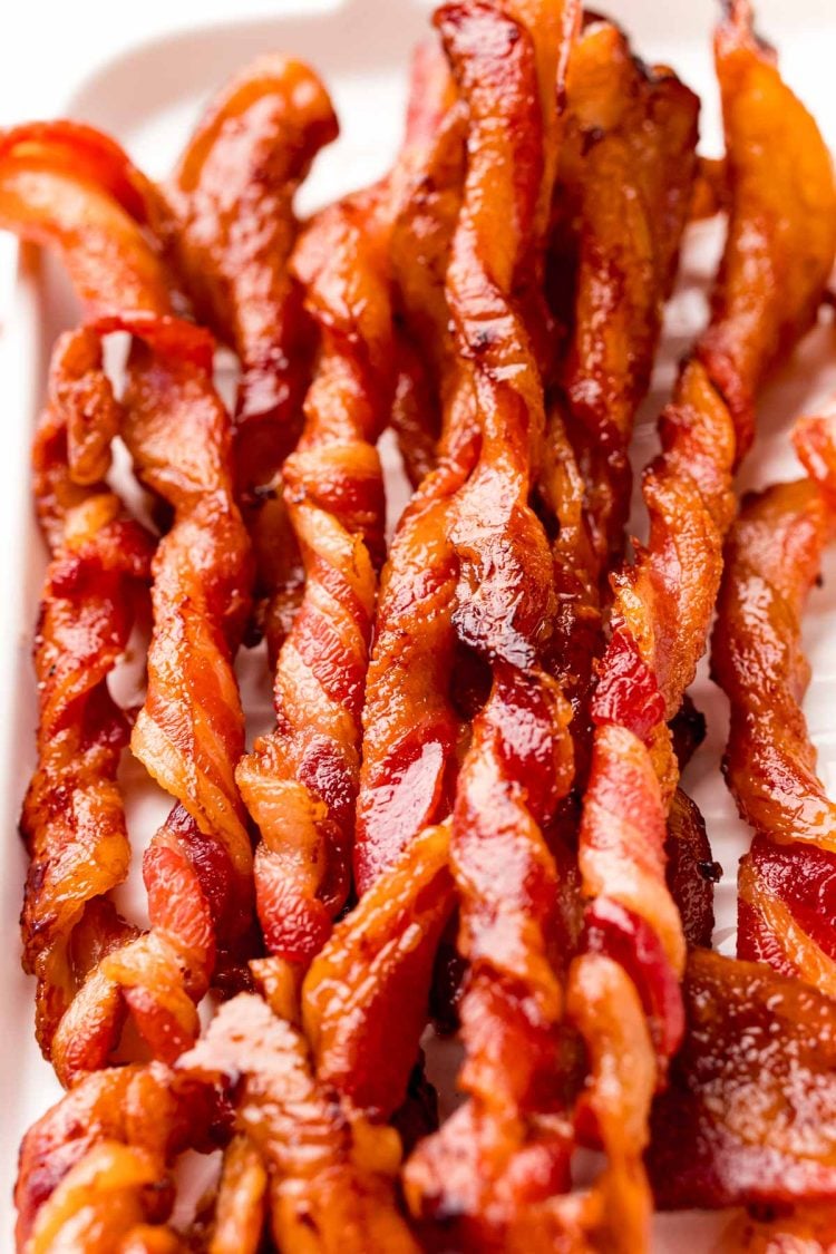 Close up photo of twisted bacon on a white serving tray.