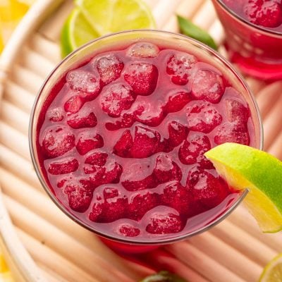 Close up photo of a woo woo cocktail garnished with lime on a wooden tray.