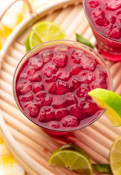 Close up photo of a woo woo cocktail garnished with lime on a wooden tray.