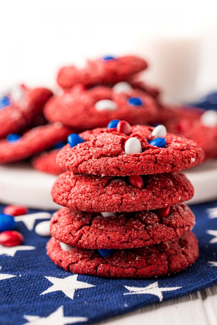 Close up photo of a stack on red velvet cookies with red, white, and blue M&Ms on a blue and white star napkin.