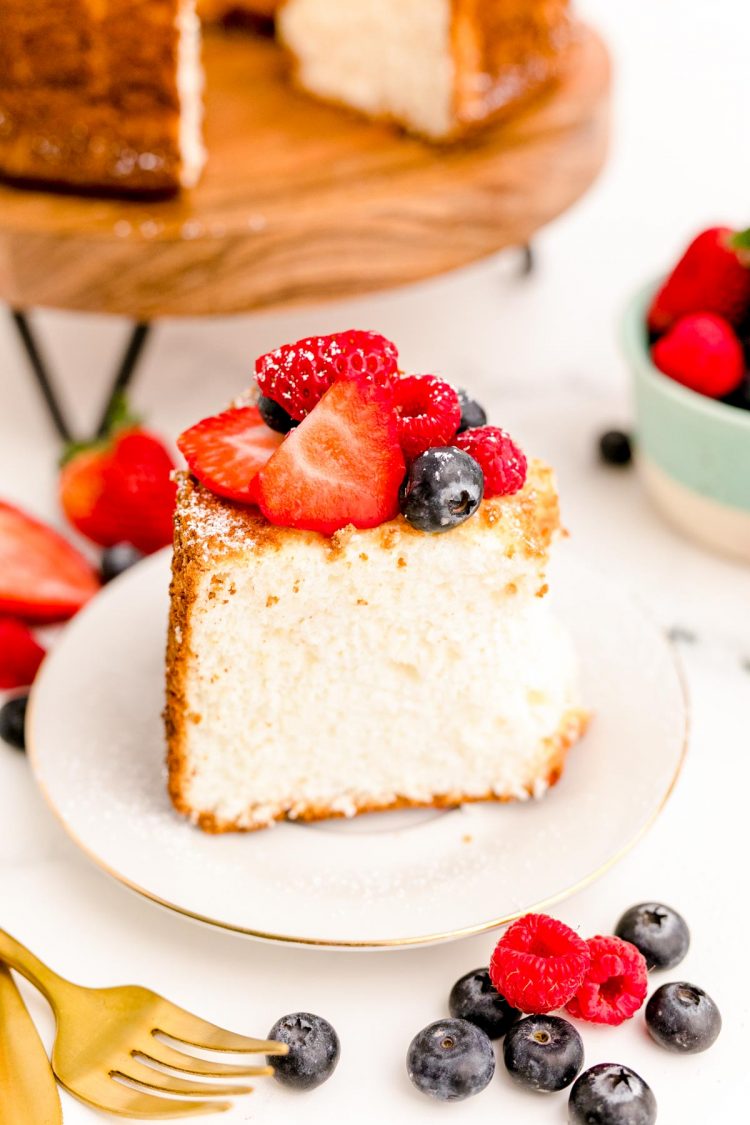 Close up photo of a slice of angel food cake topped with berries on a white plate.