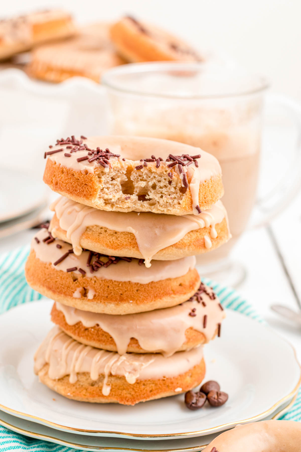 Photo of a stack of 5 coffee donuts on a white plate.