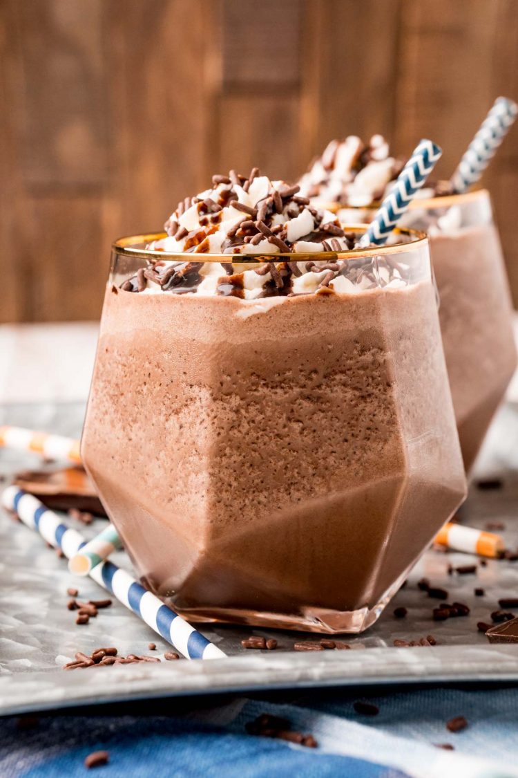 Close up photo of a glass with frozen hot chocolate in it topped with whipped cream and chocolate syrup.