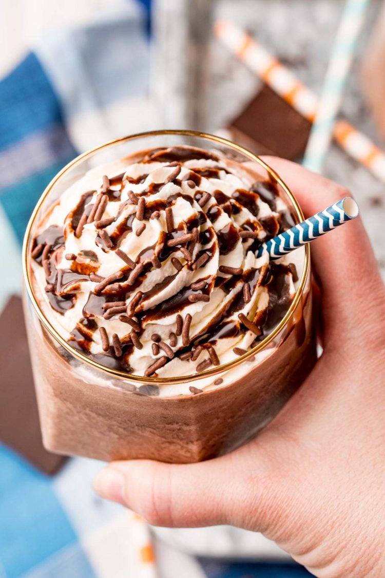 A woman's hand holding a glass of frozen hot chocolate to the camera.