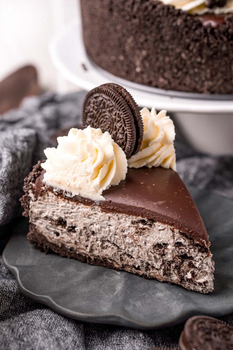 Close up photo of a slice of no-bake oreo cheesecake on a gray plate on a gray napkin.