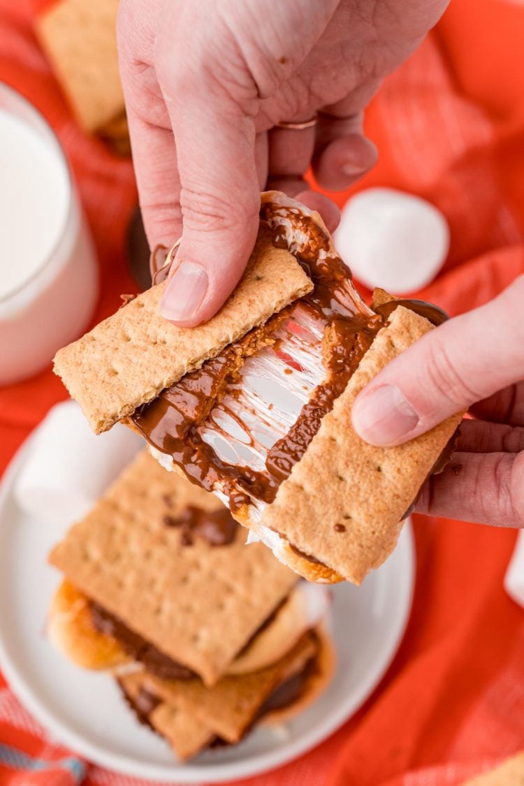 Close up photo of a woman's hand breaking an air fryer smores in half.