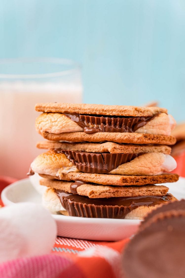 Close up photo of a stack of Reese's peanut butter cup s'mores on a white plate on an orange napkin.