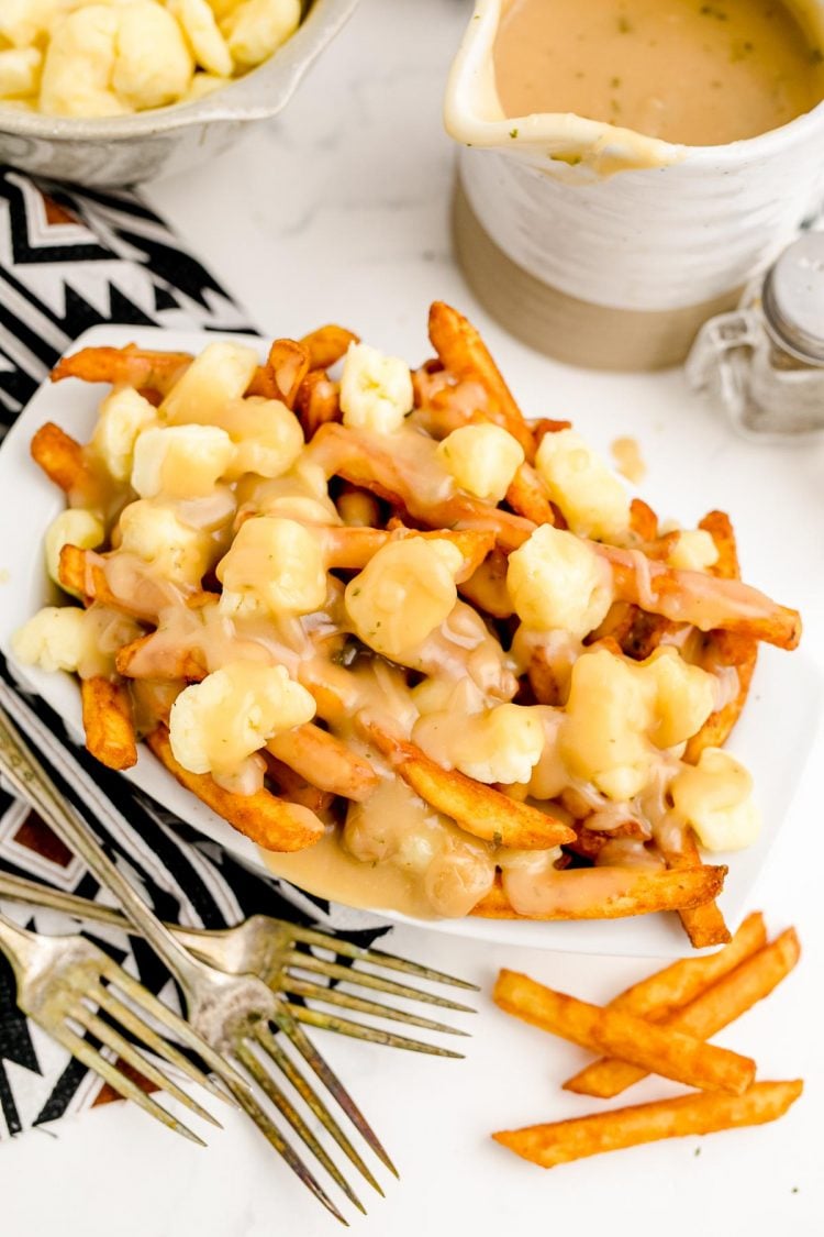 Overhead photo of a paper tray with poutine in it. Pitcher of gravy on the side.