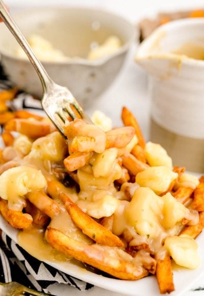 Close up photo of poutine with a fork taking a bite out of it.