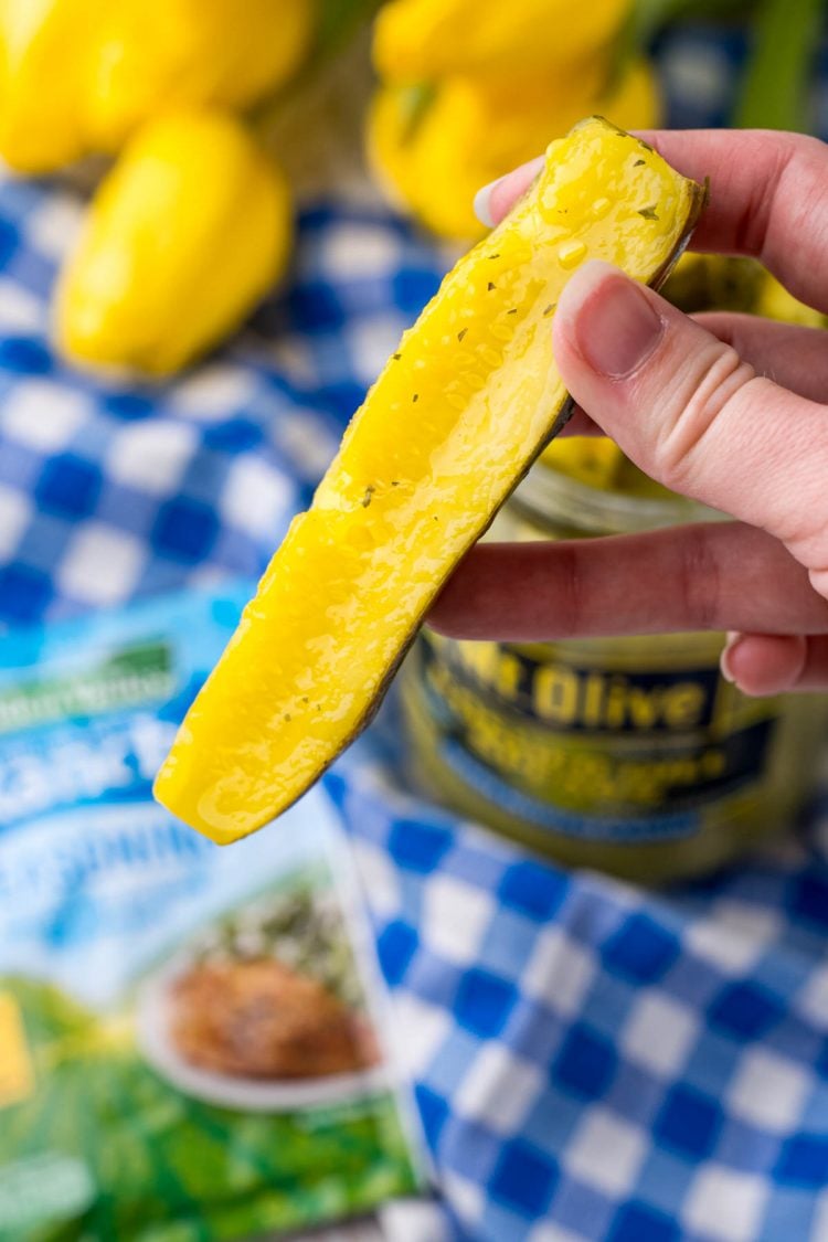 Close up photo of a woman's hand holding a ranch pickle to the camera.