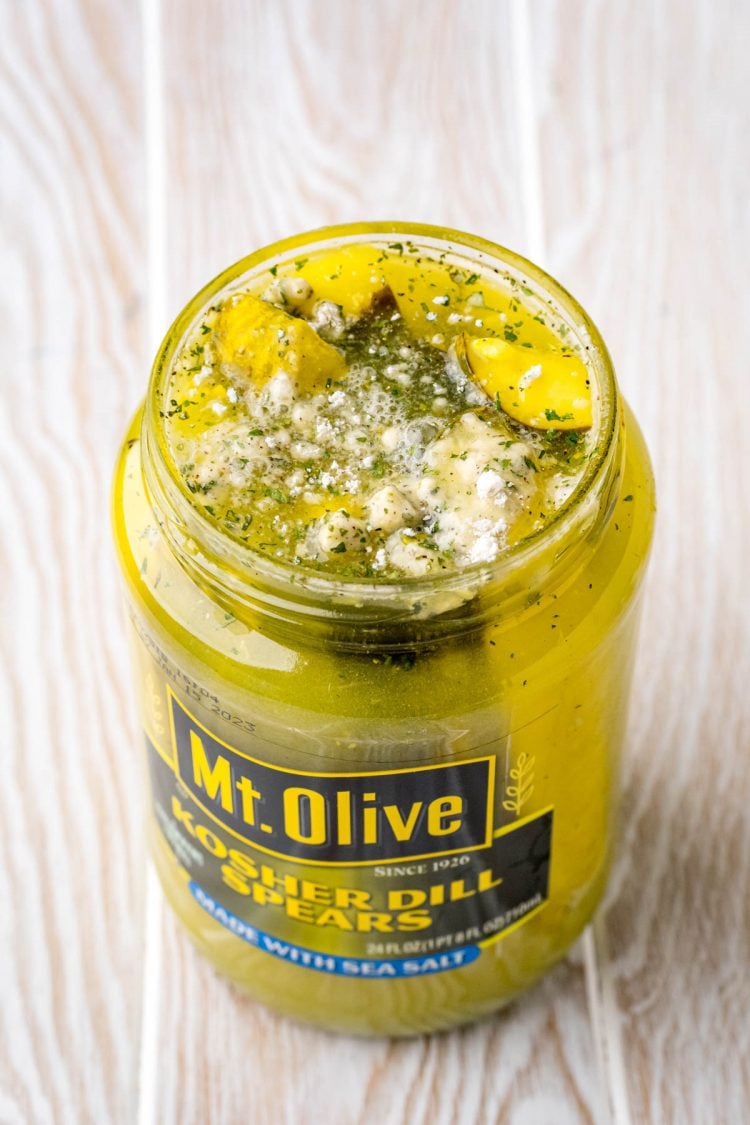 Close up photo of a jar of pickles with ranch seasoning in it.