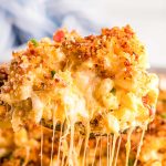 Close up photo of a serving spoon scooping mac and cheese out of a pan.