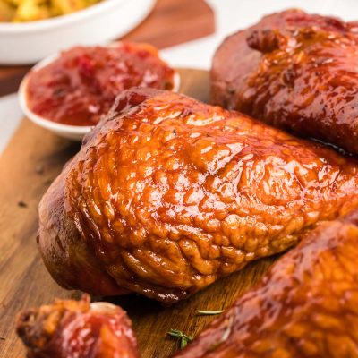 Close up photo of smoked turkey legs on a wooden cutting board.