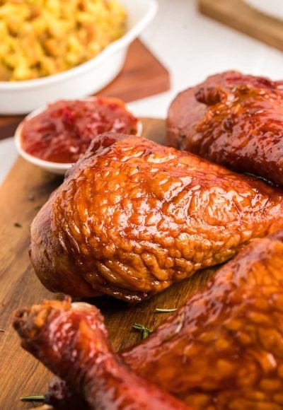 Close up photo of smoked turkey legs on a wooden cutting board.