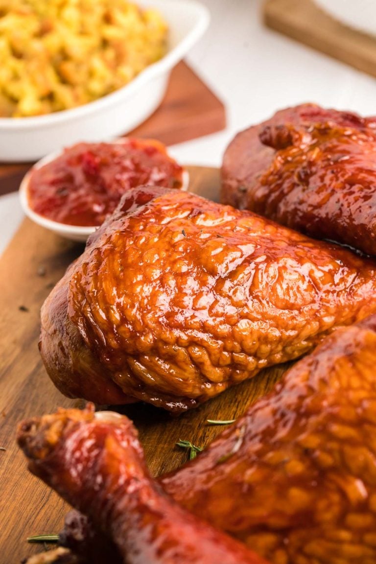 Close up photo of smoked turkey legs on a wooden cutting board.